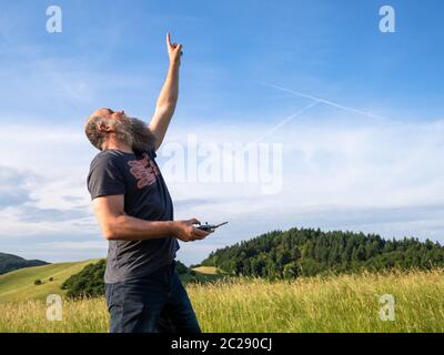 uomo che punta verso il suo drone nel cielo Foto Stock