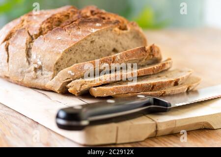 Pane fresco a fette su tagliere di legno, all'aperto Foto Stock