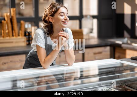 Ritratto di una giovane e felice venditore al banco di gelateria o caffetteria. Concetto di piccola impresa e vendita al dettaglio Foto Stock