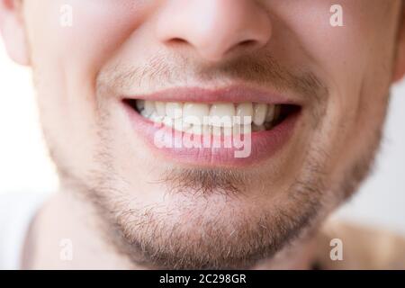 Il giovane sorride nella macchina fotografica: Denti bianchi, labbra e barba Foto Stock