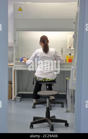 Giovane infermiera in uniforme bianca seduta in laboratorio chimico Foto Stock