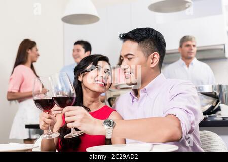 Ritratto di giovane coppia sorridente che brinda bicchieri di vino rosso nella festa Foto Stock