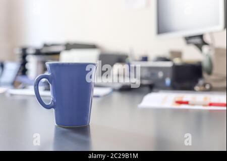 Tazza di caffè blu sulla scrivania dell'ufficio Foto Stock