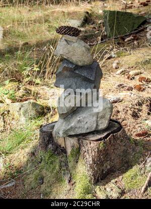 Pietre come una piramide accatastata su un ceppo di albero Foto Stock