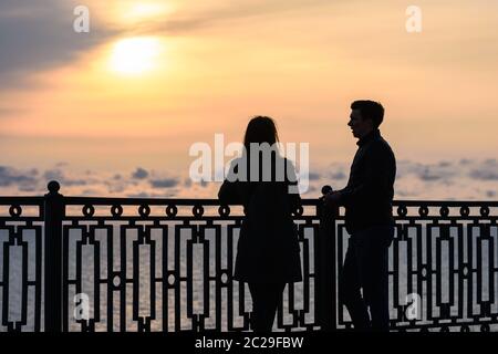 Due giovani parlano al tramonto sullo sfondo del paesaggio marino Foto Stock