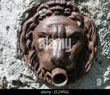 Fontana con museruola di un leone di ferro: È completamente coperta da una patina di ruggine che le conferisce il colore marrone. Foto Stock