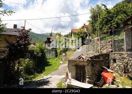 Vista su un villaggio di mezza montagna circondato da verde natura. Movimento di inclinazione, si vede la strada che si insinua tra le case. Foto Stock