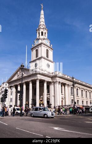 Londra, UK - 25 marzo 2012: Traffico e pedoni fuori dalla chiesa simbolo di St Martin nei campi in Trafalgar Square, Londra su una spoletta soleggiata Foto Stock