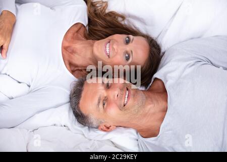 Angolo di Alta Vista di Felice Coppia Matura giacente sul letto Foto Stock