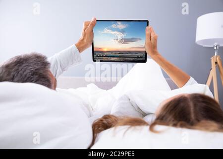 Giovane guardando film sulla tavoletta digitale mentre giaceva a letto Foto Stock
