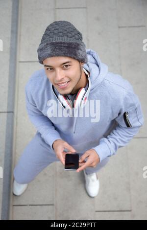 Sorridente giovane uomo latino runner formato ritratto sport invernali dalla formazione esterna di cui sopra Foto Stock