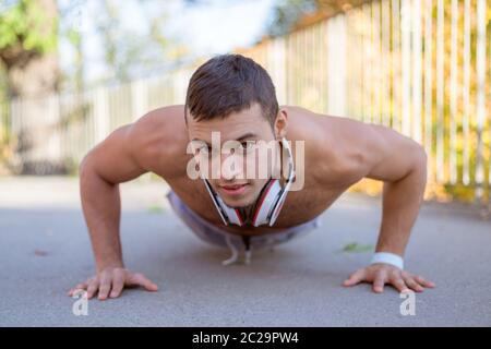 Fare push-up pushups esercizio di allenamento sportivo fitness giovane uomo latino outdoor Foto Stock