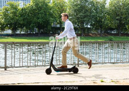 Giovane uomo che cavalca un elettrico Kick Scooter Foto Stock