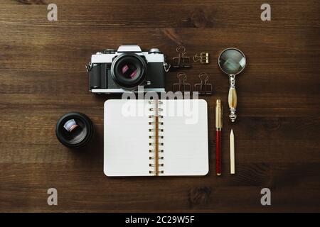 Macchina fotografica con pellicola d'epoca, obiettivi e cancelleria su tavolo di legno scuro, rustica a posa piatta Foto Stock