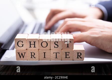 Un Ghostwriter blocco di legno sulla tastiera del computer mentre qualcuno digita Foto Stock