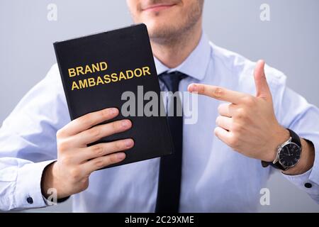 Uomo con Libro con Ambasciatore del marchio testo e puntamento Foto Stock