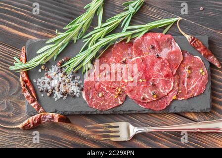 Carpaccio - fette di carne di manzo crudo sulla scheda di pietra Foto Stock