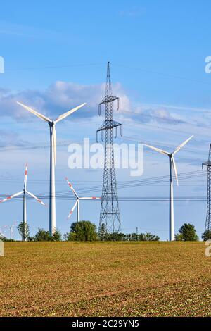 Un traliccio di elettricità e generatori di energia di vento visto in Germania Foto Stock