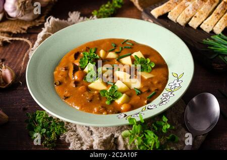 Semplice ma una delizia di zuppa, aglio fresco e erbe con pomodori e funghi di bosco appena raccolte Foto Stock