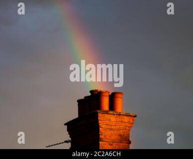 Arcobaleno che appare da dietro un camino Foto Stock