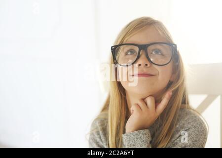 Sorridente ragazza carina con occhiali neri su sfondo bianco. Foto Stock