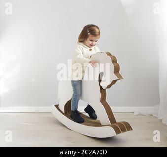 Adorabile bambina seduta su cavallo a dondolo Foto Stock