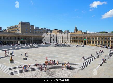 le persone si rilassano sui gradini e nei caffè godendo del sole estivo nella piazza della sala pezzi halifax nella parte occidentale dello yorkshire Foto Stock