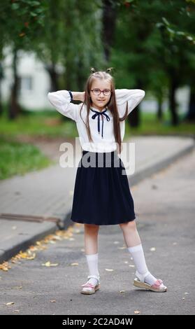 Da studentessa in una scuola in posa uniforme. Bambino ragazza sorge all'esterno. Colpo verticale. Messa a fuoco selettiva. Foto Stock