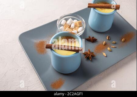 Due tazze blu con tradizionale tè indiano masala chai con spezie e zucchero su un vassoio in ceramica su sfondo chiaro. Messa a fuoco selettiva, spazio di copia Foto Stock