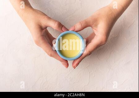Le mani delle donne nella forma di una tazza blu di ceramica di tenuta del cuore con il tè indiano tradizionale masala chai. Vista dall'alto con spazio per la copia Foto Stock