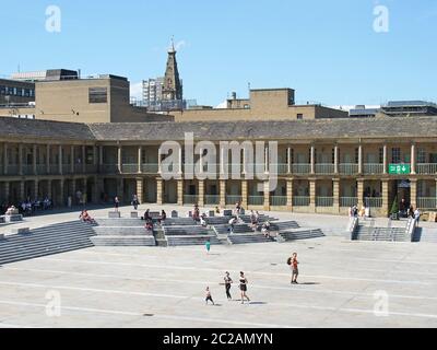 le persone si rilassano sui gradini e nei caffè godendo del sole estivo nella piazza della sala pezzi halifax nella parte occidentale dello yorkshire Foto Stock