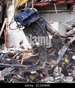 un primo piano di un artiglio da demolizione pesante che raccoglie detriti e macerie in un cantiere Foto Stock