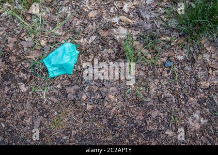 Maschera protettiva per la protezione contro il coronavirus gettato nella foresta. Il concetto di littering l'ambiente durante una pandemia Foto Stock