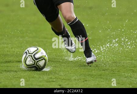 Primo piano gambe di giocatori di calcio femminile in azione, su un campo di calcio verde bagnato. Foto Stock