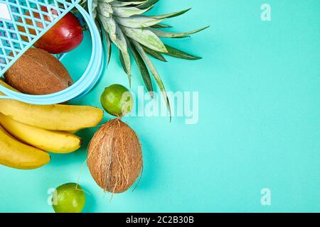 Borsa della spesa della drogheria con frutta esotica biologica su sfondo blu. Piatto di varietà di frutta tropicale fresca che si spillano da una borsa riutilizzabile. Foto Stock