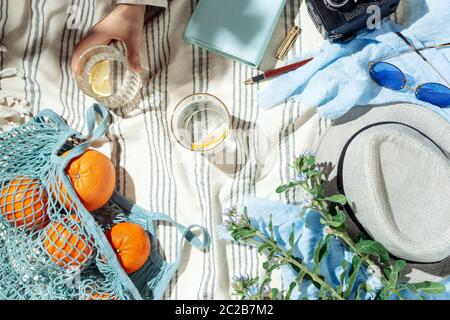 Femminile estate pic-nic flatlay, frutta, frutti di bosco e acqua di limone su coperta di cotone a righe Foto Stock