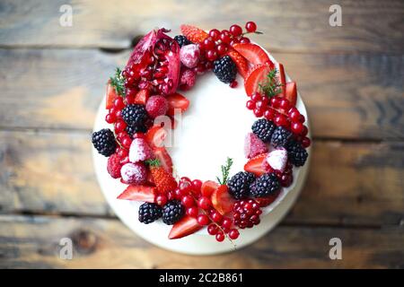 Torta di Natale decorata con frutti di bosco sul tavolo di legno Foto Stock