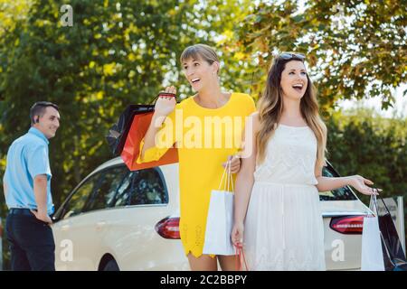 Le donne con le borse della spesa in uscita del taxi, il conducente in piedi in background Foto Stock