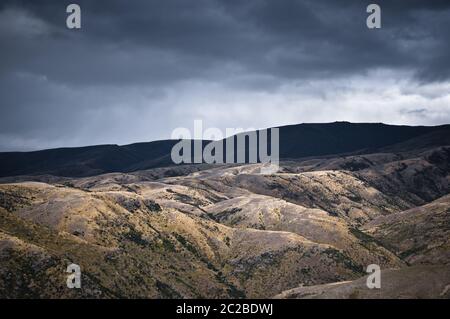 Le colline texturali all'estremità meridionale della Lindis Valley a Otago, Nuova Zelanda, in una giornata di lavoro. Foto Stock