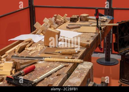 Laboratorio di falegnameria. Un banco di lavoro in una falegnameria con strumenti professionali che il falegname utilizza. Seghe, morsetti a vite, mazzuolo e piano in legno. Foto Stock