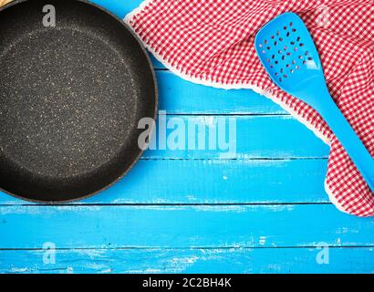 Vuoto nero tondo nonstick padella con manico in legno di colore blu con sfondo rosso igienico, vista dall'alto Foto Stock