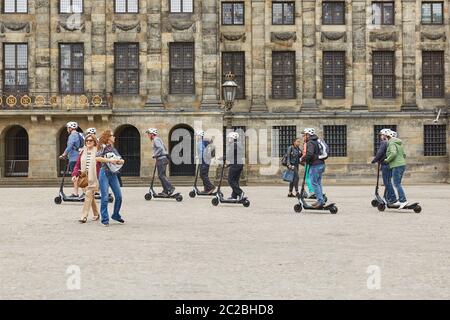 Persone che cavalcano scooter di fronte al Palazzo reale e attraverso il centro di Amsterdam Paesi Bassi Foto Stock