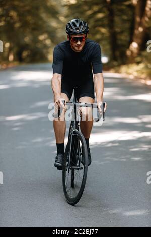 Elegante, sportivo, uomo barbuto in abbigliamento sportivo e casco, seduto  in bicicletta sulla strada in campo nelle serate estive più fredde Foto  stock - Alamy