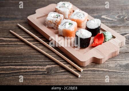 Tre diversi tipi di rotoli giapponese con wasabi e zenzero sul vassoio di bambù sul bellissimo sfondo di legno Foto Stock