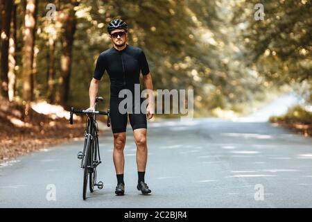 Elegante, sportivo, uomo barbuto in abbigliamento sportivo e casco, seduto  in bicicletta sulla strada in campo nelle serate estive più fredde Foto  stock - Alamy