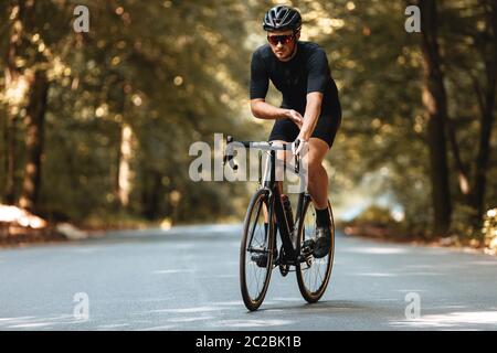 Ciclista professionale con portacolori in abbigliamento sportivo e casco protettivo con moto sulla natura. Sportivo disciplinato che svolge attività regolare su fr Foto Stock