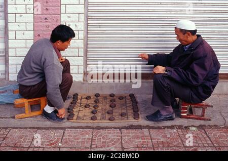 Uomini cinesi che giocano Xiangqi anche chiamato scacchi cinesi che è un gioco di strategia da tavolo in un marciapiede nella città di Tongren nella provincia di Guizhou Cina Foto Stock