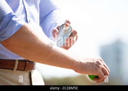 L'uomo la spruzzatura anti insetto Deet Spray sulla pelle sopra il suo braccio all'aperto Foto Stock