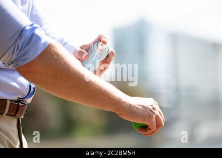 L'uomo la spruzzatura anti insetto Deet Spray sulla pelle sopra il suo braccio all'aperto Foto Stock