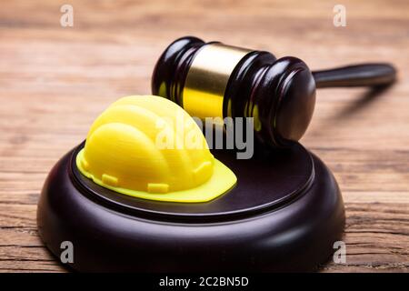 Angolo di Alta Vista di Casco giallo e martello disposti sulla scrivania in legno Foto Stock